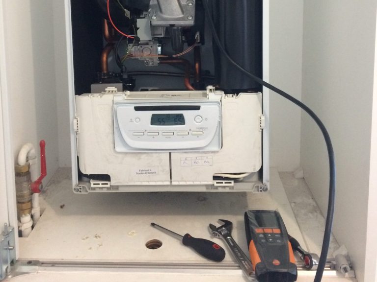 Chaudière installée dans un petit espace avec un outils de de mesure de fumée à proximité.